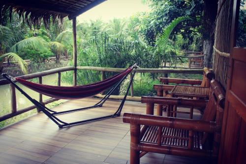 a hammock on a porch with a view of the jungle at Green Village Mekong in Can Tho