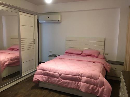 a bedroom with a pink bed and a mirror at Ramco For Furnished Apartments And Accommodation Compound Leila in Cairo