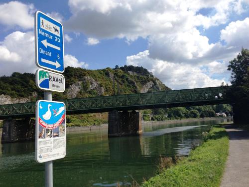 a green bridge over a river with signs on it at L'Ecole in Dinant