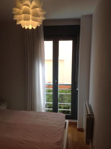 una camera con letto, finestra e lampadario a braccio di Nice stay a Madrid