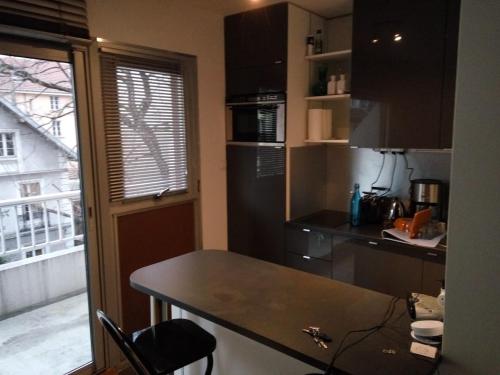 eine kleine Küche mit einem Tisch und einem Balkon in der Unterkunft Appartement 2 pieces 40 m2, dans hyper centre, avec piscine au rez de chaussee in Grenoble