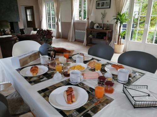 a table topped with plates of food and orange juice at Le Clos Bel Ami Chambre d'hôtes avec piscine in Bec-de-Mortagne