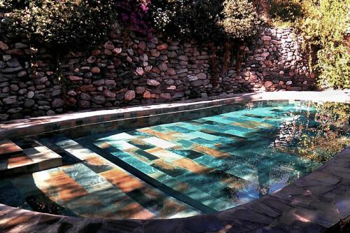 a pool of water with a stone wall at Casa Champasak in Órgiva