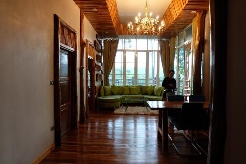 a woman standing in a living room with a green couch at One khaokho homestay in Khao Kho