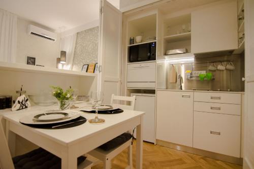 Una cocina blanca con una mesa con platos encima. en Studio Stil, en Belgrado