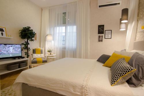 a bedroom with a white bed and a television at Studio Stil in Belgrade