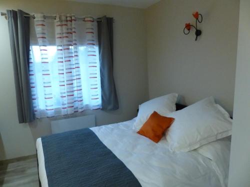 ein Schlafzimmer mit einem Bett mit weißen Kissen und einem Fenster in der Unterkunft AU CLOS DE L'ETANG in Ravel