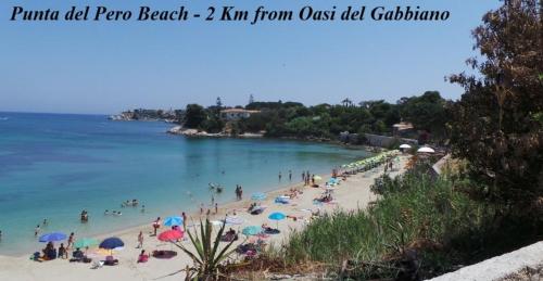 a group of people on a beach with umbrellas at Oasi Del Gabbiano in Siracusa