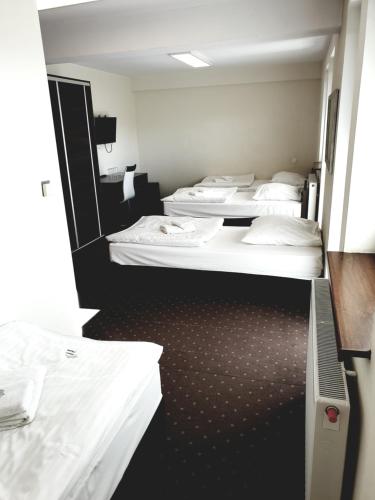 a row of four beds in a room at Perła Podhala in Szaflary