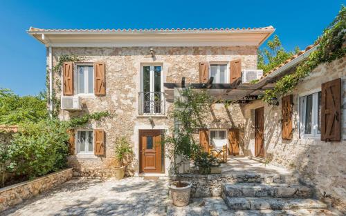 an old stone house with wooden doors and windows at Villa Callisto- Elegant Restored Villa with Pool in Yírion