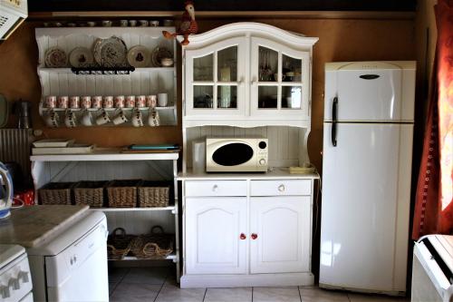 La cuisine est équipée de placards blancs et d'un réfrigérateur blanc. dans l'établissement Gite Loredana, à Kirchberg