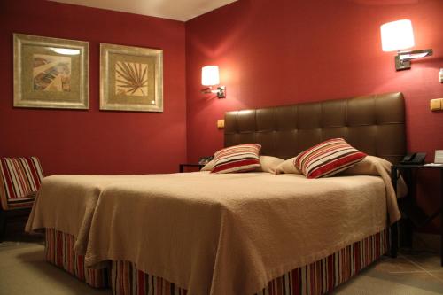GaldeanoにあるHotel Palacio Dos Olivosの赤い壁のベッドルーム1室(大型ベッド1台付)