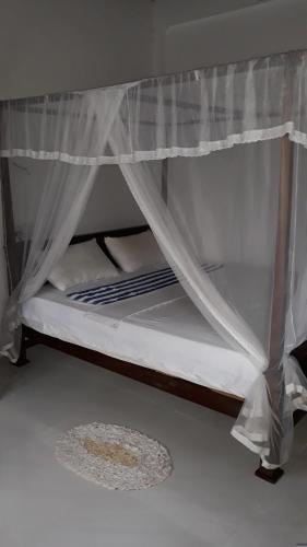 Litera con cortinas blancas y colchón en Kalpa Place Hiriketiya, en Hiriketiya