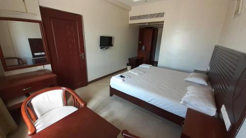 a hotel room with a bed and a chair in it at Hotel Balaji Inn in Thanjāvūr