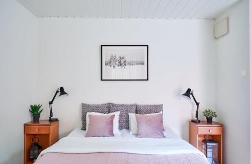 a bedroom with a bed with pink pillows and two lamps at Hotel Villa Molnby in Porvoo