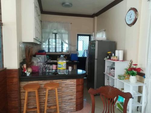 a kitchen with a counter with two chairs and a refrigerator at Juliet Guest House near Enchanted Kingdom in Balibago