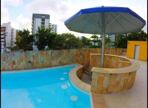 an umbrella sitting next to a swimming pool at Flat mobiliado praia, João Pessoa PB PROMOÇÃO in Cabedelo