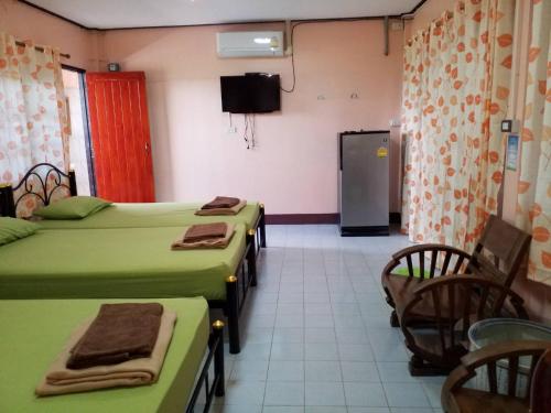 a room with four beds and chairs and a television at Punnpannsuk in Trat