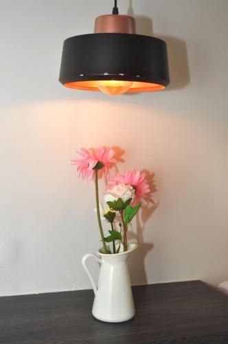 a vase with pink flowers sitting on a table under a light at De Luna Hotel Sri Petaling in Kuala Lumpur