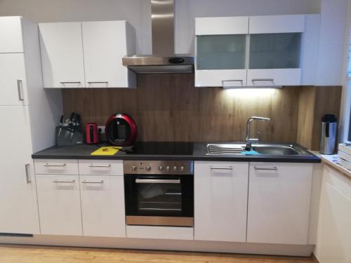 Una cocina con gabinetes blancos y un fregadero. en Ausseeerland, en Bad Aussee