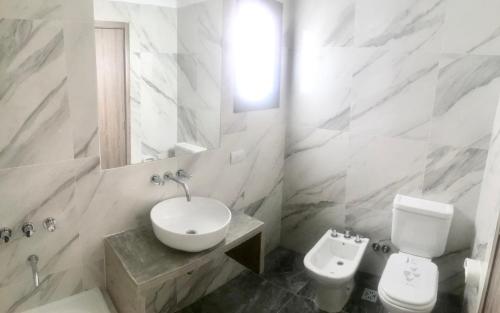 La salle de bains blanche est pourvue d'un lavabo et de toilettes. dans l'établissement Hermoso Ambiente a Estrenar, à Buenos Aires