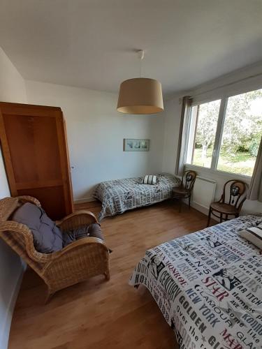 une chambre avec deux lits et une chaise et une fenêtre dans l'établissement Gites Nature & Espace - Le puits des souhaits, à Villedieu-les-Poêles