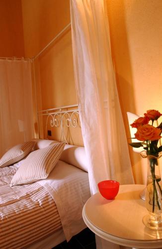 a bedroom with a bed with a vase of flowers on a table at Relais Poggio al Vento in Pomarance