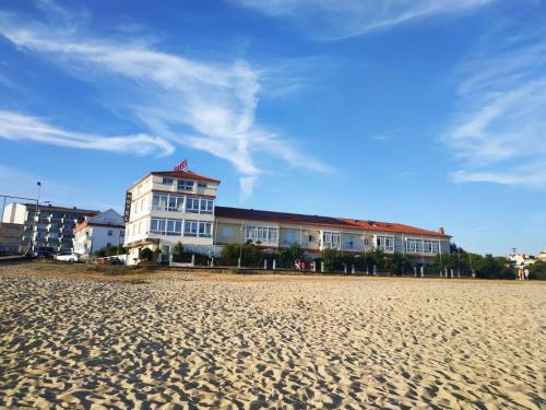 Hotel Playa في كانجاس دي مورازو: مبنى على الشاطئ بجوار شاطئ رملي