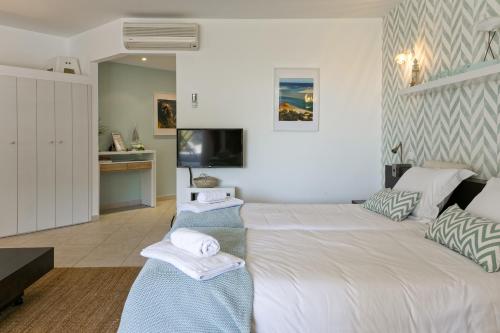 a bedroom with a large white bed and a tv at CozyHome - Cabanas in Cabanas de Tavira