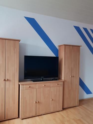 Cette chambre comprend 2 placards en bois et une télévision à écran plat. dans l'établissement Ferienwohnung Hesse, à Grimma