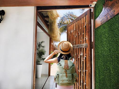 a woman with a hat standing outside a door at Puerto Bamboo in Máncora