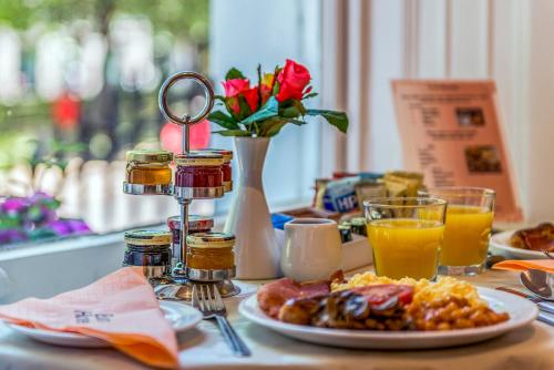 a table with a plate of breakfast food and a vase with flowers at Euro Hotel in London