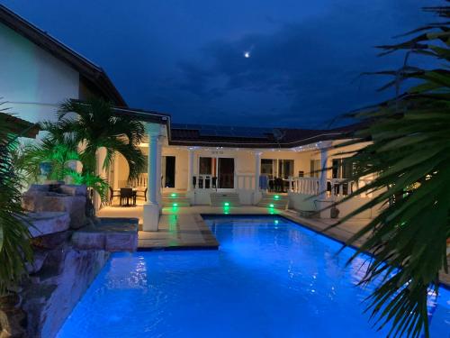 a swimming pool in front of a house at night at Boutique Hotel Swiss Paradise Aruba Villas and Suites in Palm-Eagle Beach