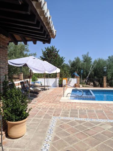 a patio with an umbrella and a swimming pool at La Noguera de Baena in Baena