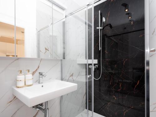 a bathroom with a sink and a shower at Lofts Cracow Apartments - City Center in Krakow