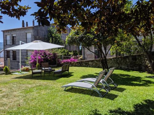 ein paar Stühle und ein Regenschirm im Gras in der Unterkunft Hotel A Torre do Xudeu in Tui