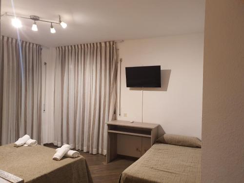 a hotel room with two beds and a flat screen tv at Pensió Costa Brava in Sant Antoni de Calonge