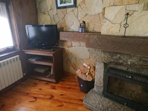 a living room with a stone fireplace and a television at Artesano II in Navarredonda de Gredos