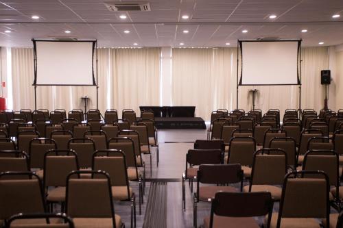 an empty conference room with chairs and blank screens at Druds Hotel Hortolândia in Hortolândia