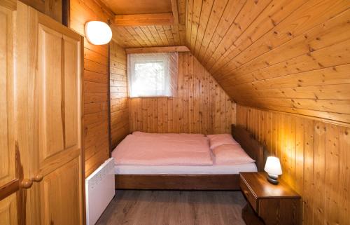a small room with a bed in a wooden cabin at Chata Kadlečka in Lipno nad Vltavou