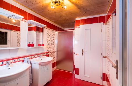 baño con 2 lavabos y azulejos rojos en Chata Kadlečka, en Lipno nad Vltavou