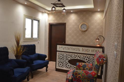 a living room with chairs and a clock on the wall at Pyramids Top Inn in Cairo