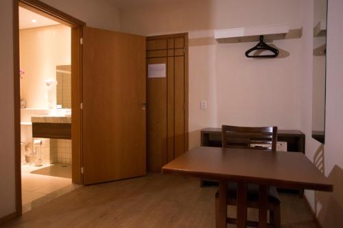 a dining room with a table and a door to a kitchen at Druds Hotel Hortolândia in Hortolândia