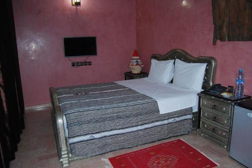 a bedroom with a bed and a tv on the wall at Riad les jardins Mabrouk in Taroudant