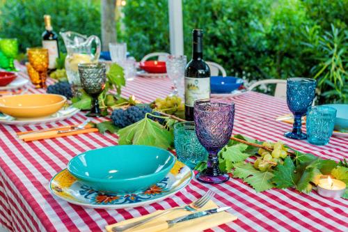 a table with a red and white checkered table cloth with wine bottles at Villa Pongina with private pool in Montevarchi