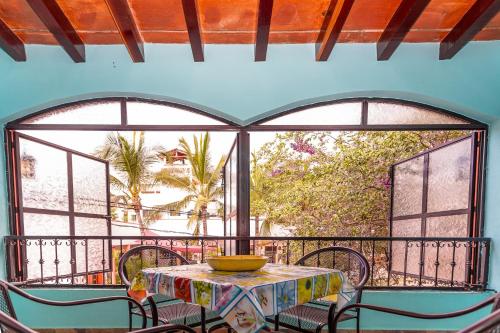 een tafel en stoelen op een balkon met ramen bij Villa Celeste in Chacala