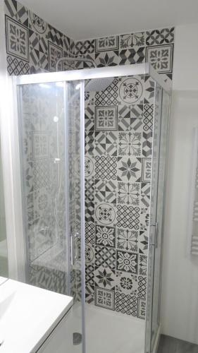 La salle de bains est pourvue d'une douche avec du carrelage noir et blanc. dans l'établissement Appartement cosy proche gare, à Vierzon