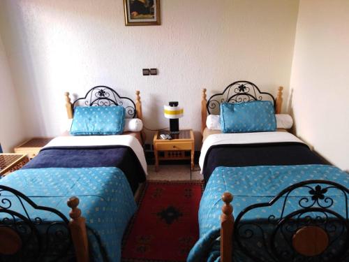 duas camas num quarto com lençóis azuis e pretos em Hotel Tiout em Taroudant