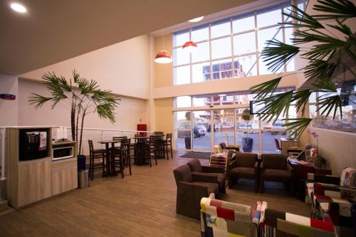 a waiting room with couches and tables and a large window at Druds Hotel Hortolândia in Hortolândia