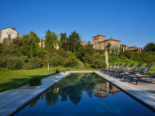 a swimming pool with chairs and a castle in the background at Il Castello di Tassara in Tassara